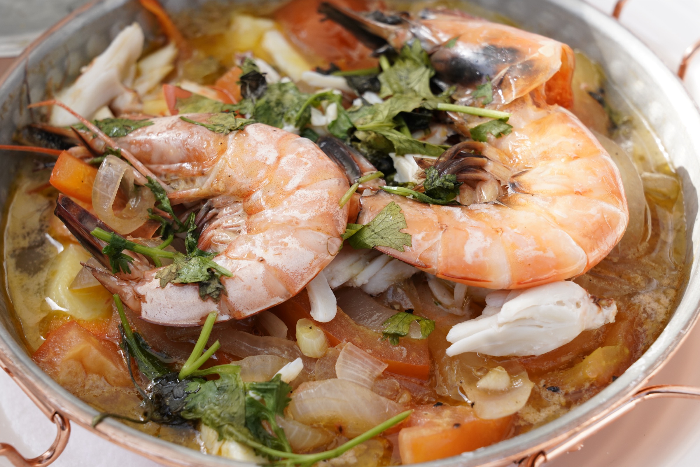 Cataplana de fruits de mer ouverte, marmite de cuivre portugaise révélant crevettes, moules et palourdes