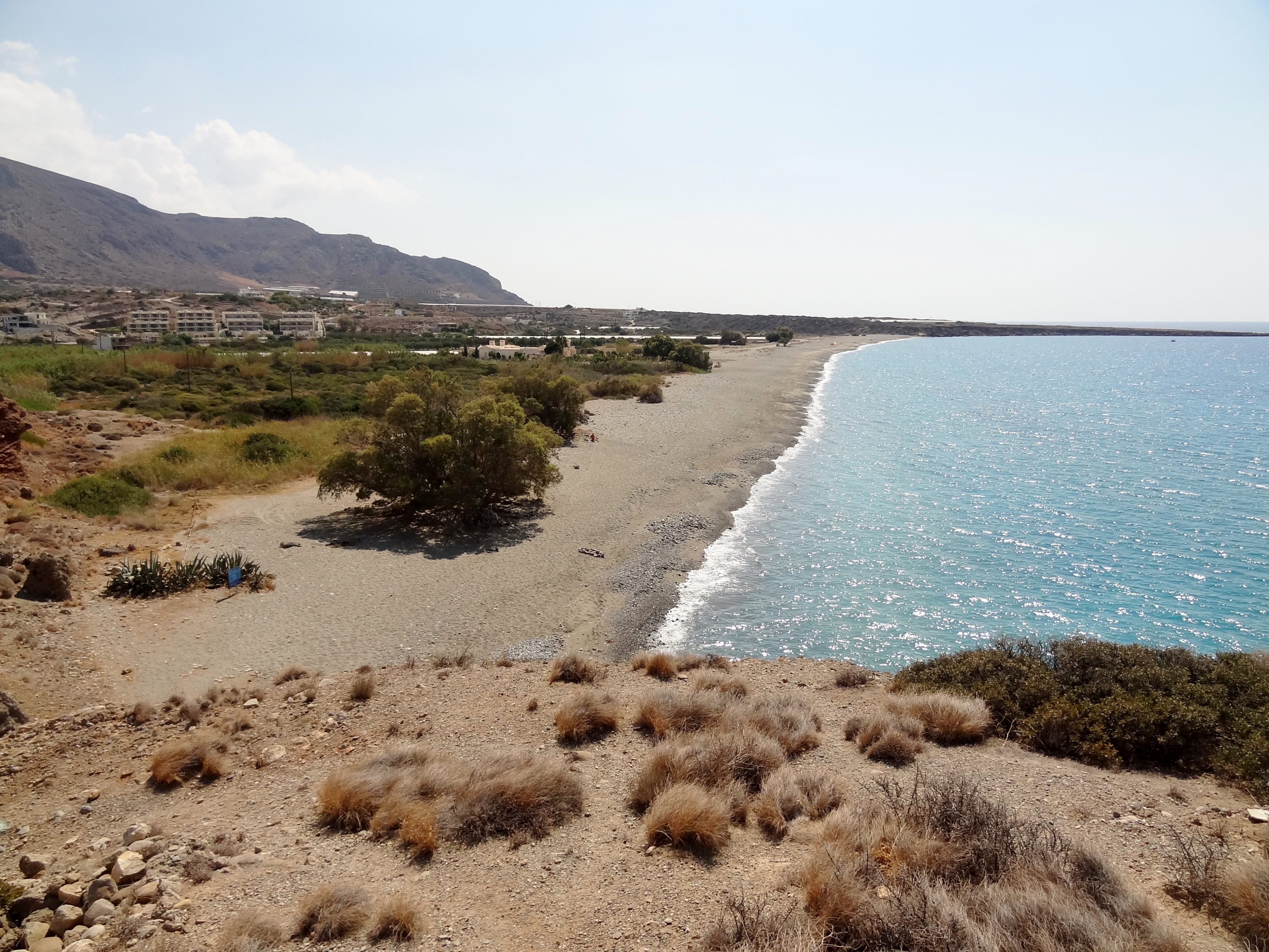 Une longue plage de galets de la baie d'Aegiali, au nord d'Amorgos, bordée de collines arides et d'une eau bleue claire