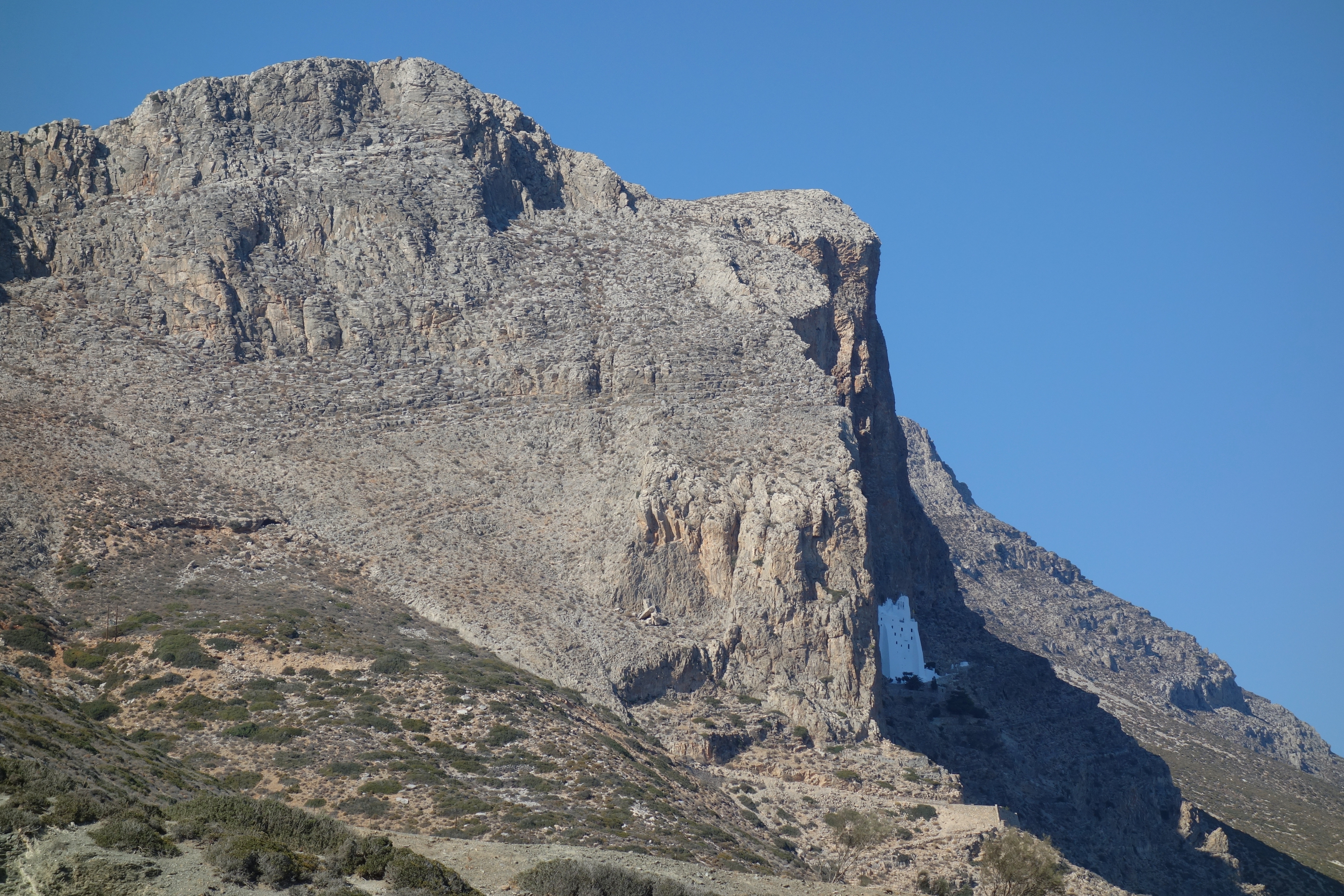L'immense montagne rocheuse de la côte est d'Amorgos, avec le minuscule monastère blanc de Hozoviotissa accroché à mi-falaise, vu depuis la plage d'Agia Anna