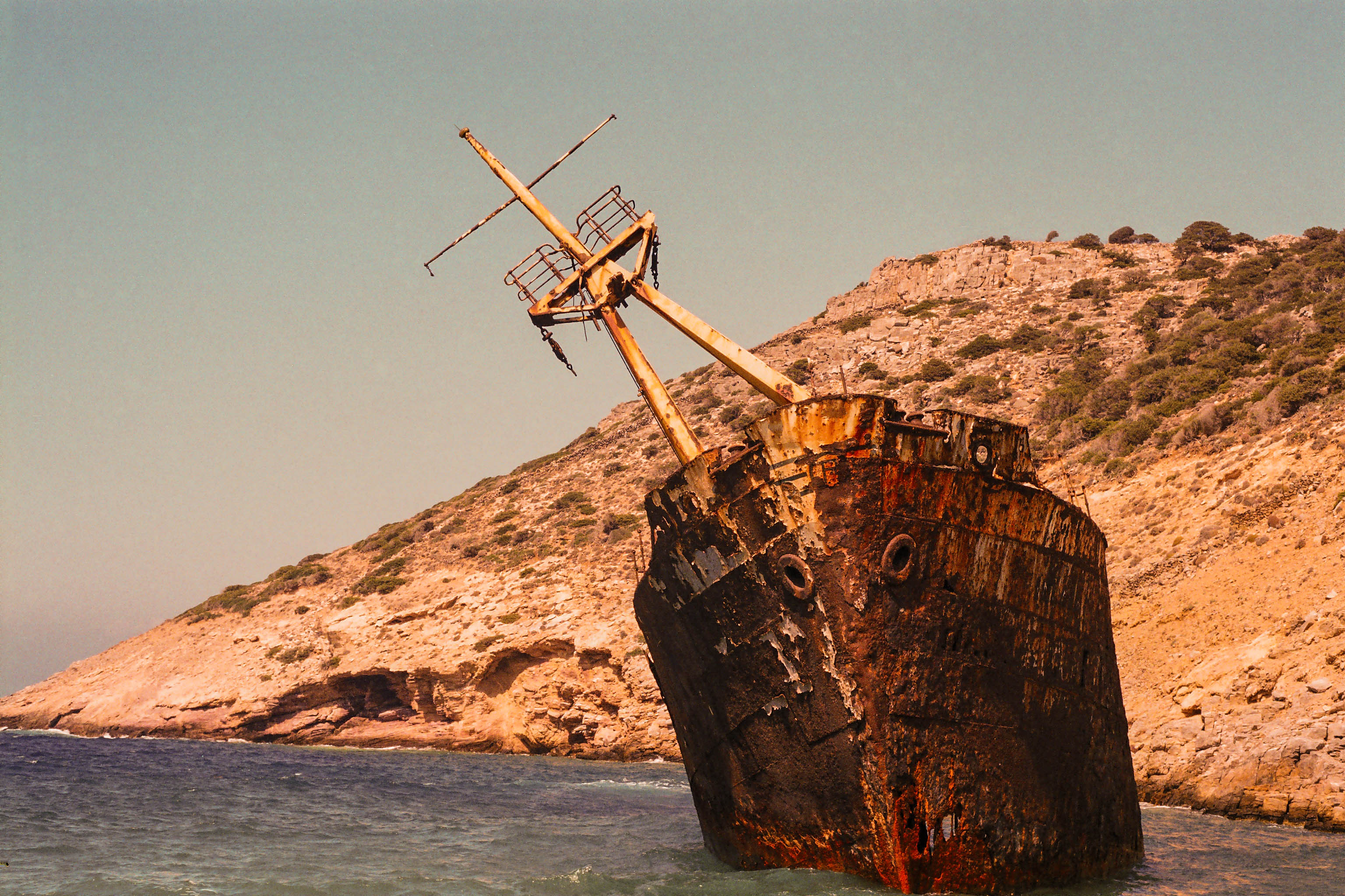 L'épave rouillée du cargo Olympia échouée dans une eau turquoise au pied de collines arides à Amorgos (la plage de Kalotaritissa), en lumière dorée
