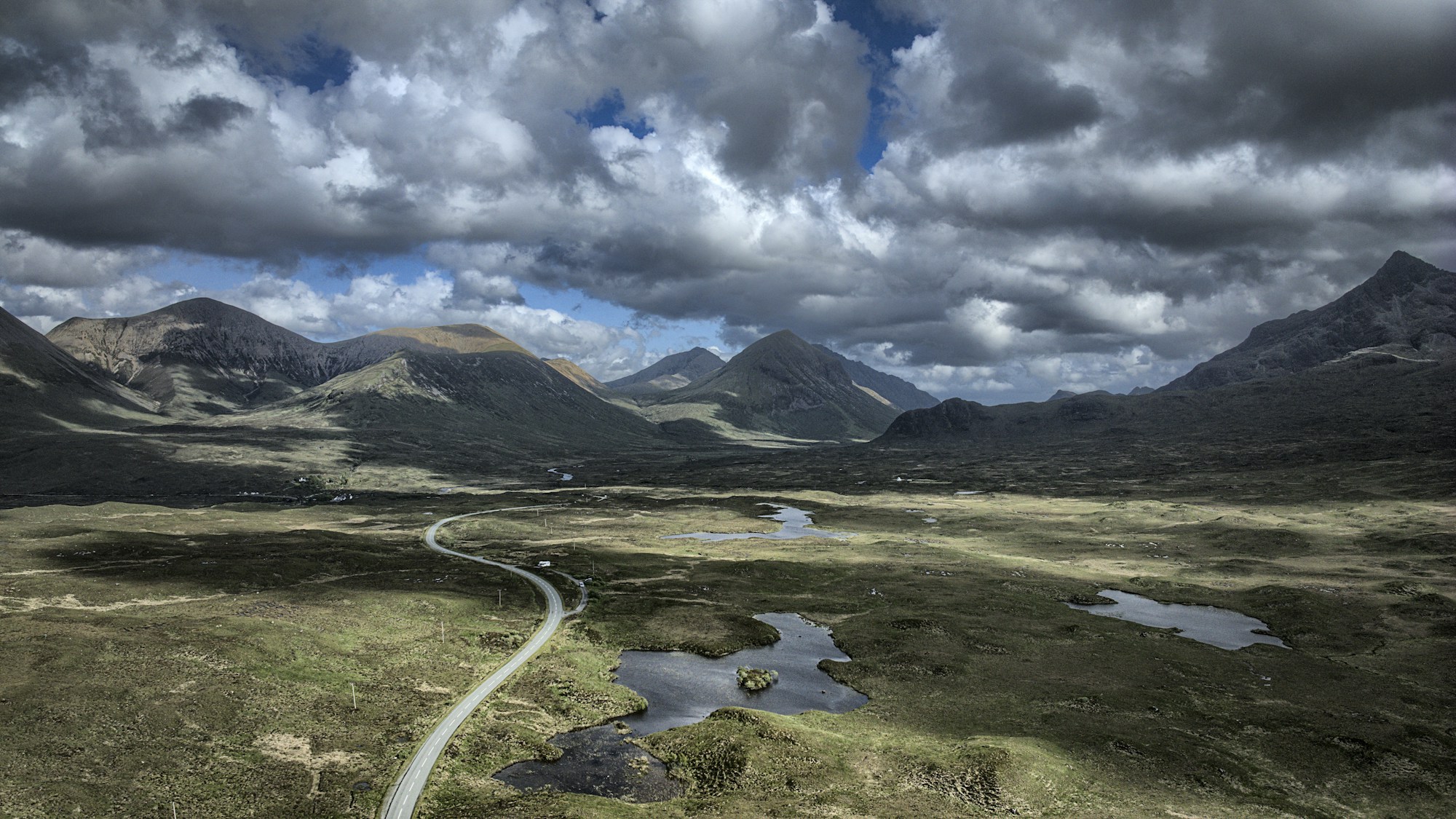 A road winding through the green mountains of the Isle of Skye.