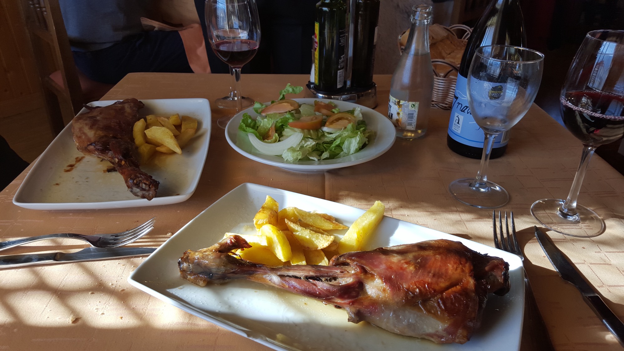Une assiette de cabrito (chevreau) rôti avec des pommes de terre, sur une table de restaurant