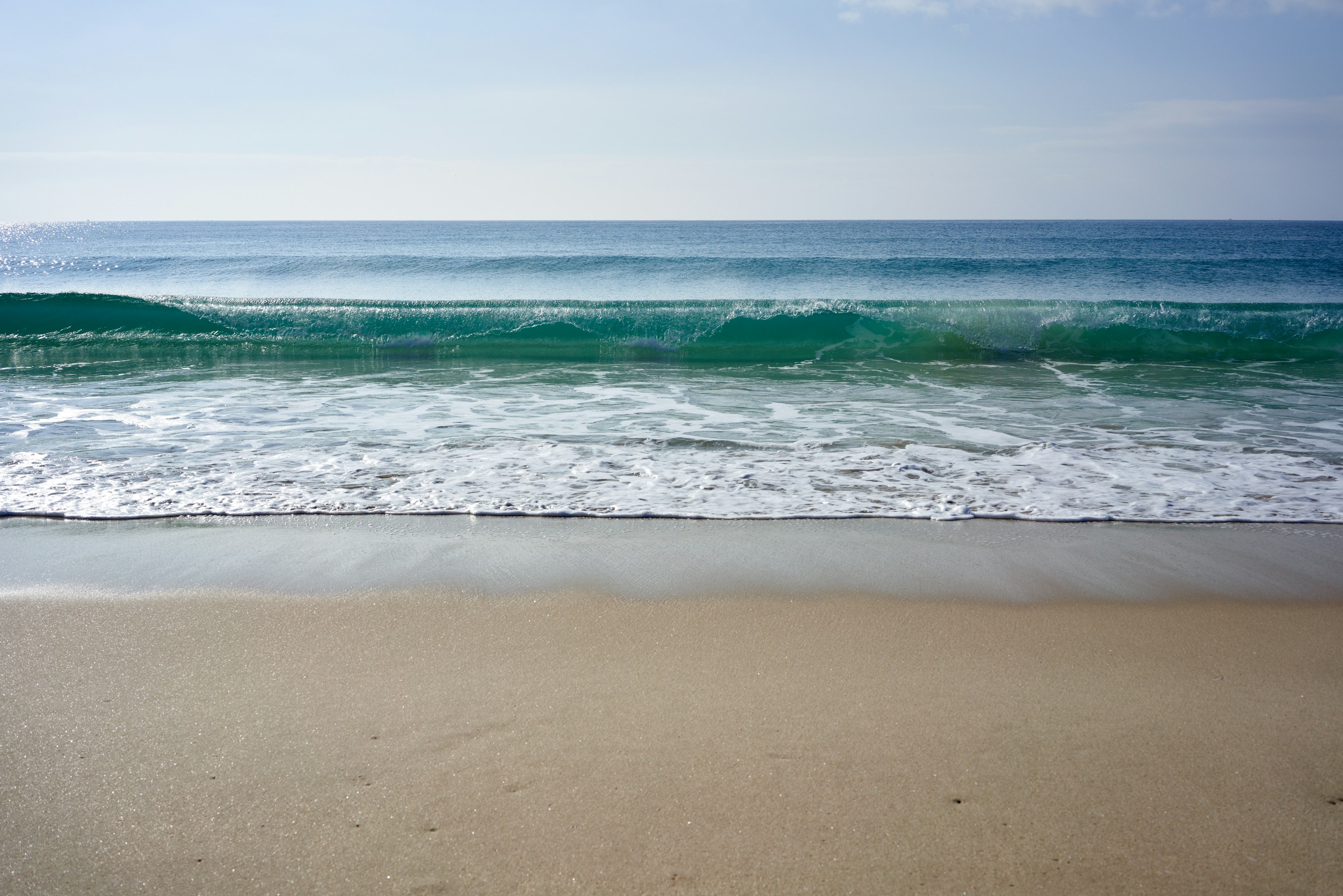 Vague atlantique déferle sur la vaste plage de sable de Comporta, côte sauvage de l'Alentejo, Portugal