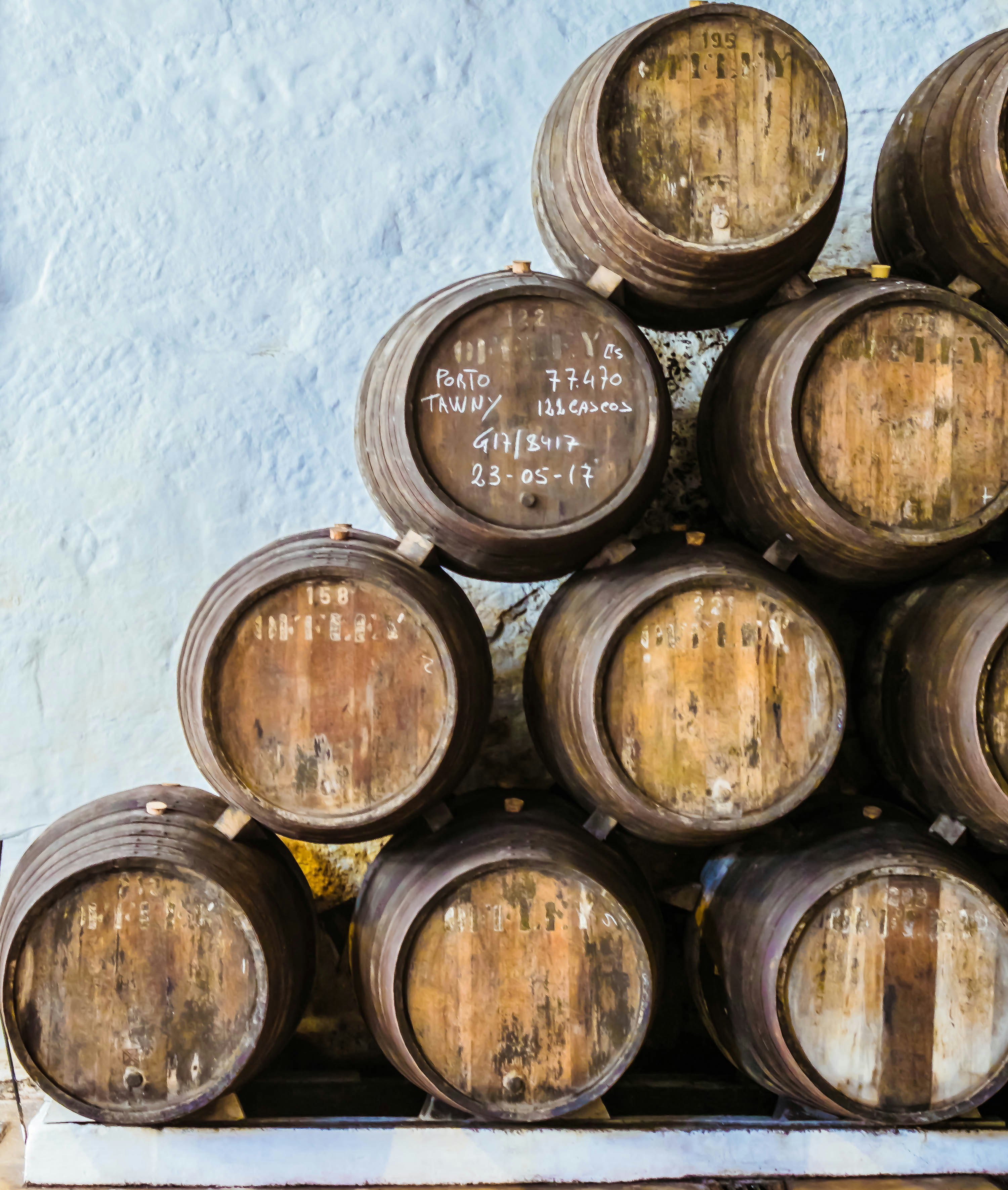 Rangées de barriques de porto dans la cave Offley à Vila Nova de Gaia — fûts de chêne empilés dans l'obscurité d'un chai historique de production de vin de porto.