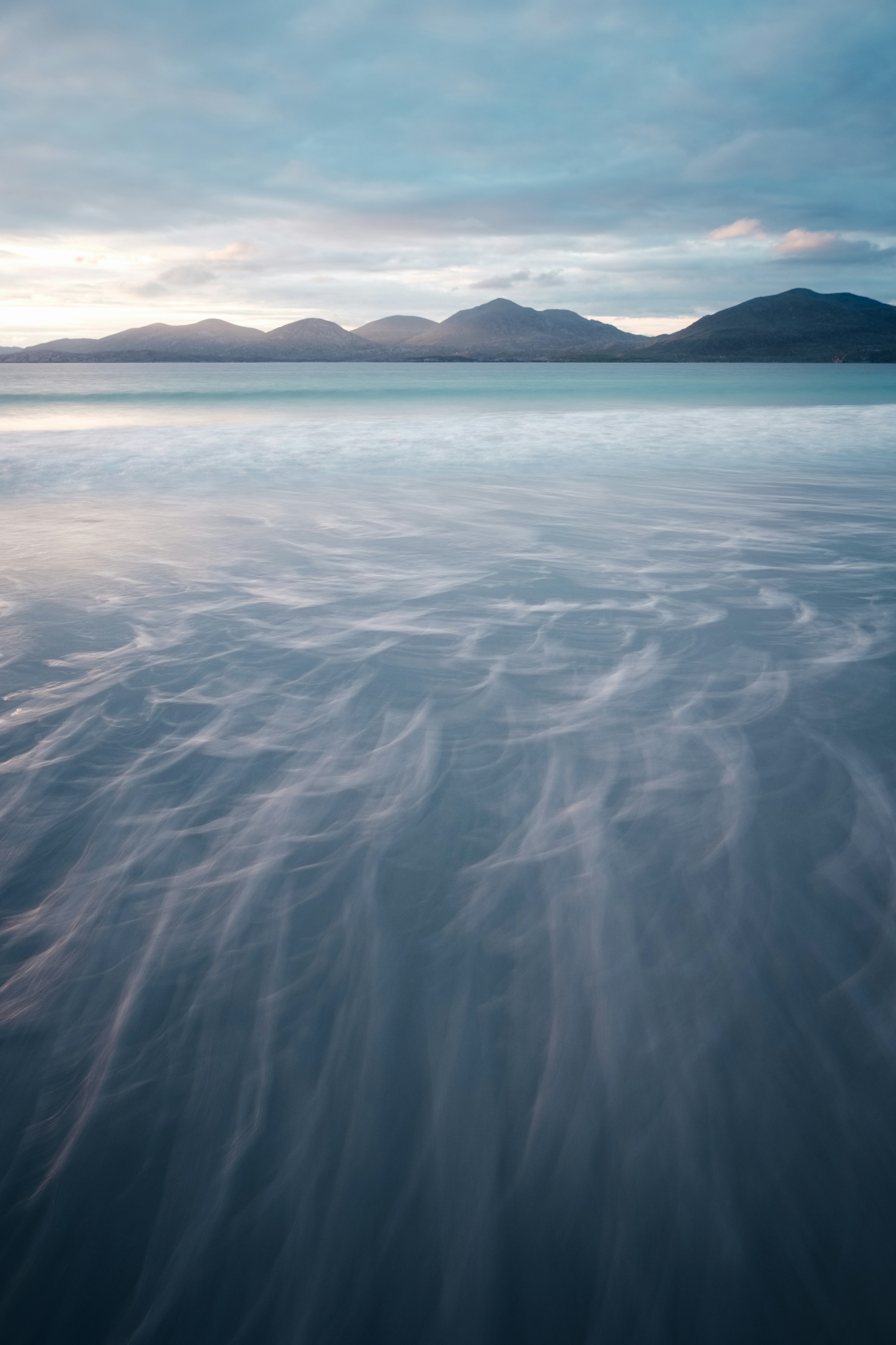 Turquoise water meeting white sand at Luskentyre with hills across the sound