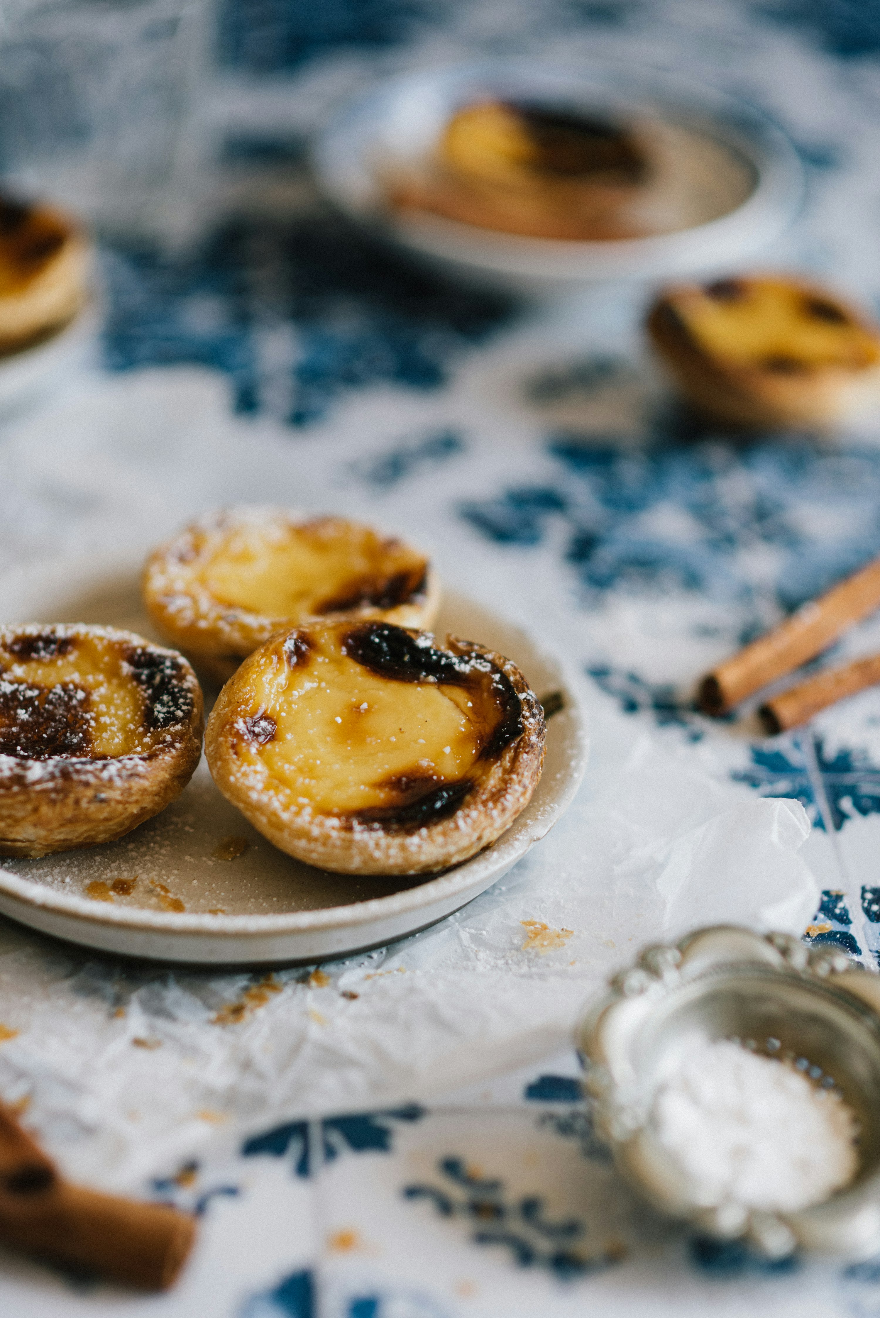 Pastéis de nata — tartelettes à la crème portugaises sur assiette avec leur coque feuilletée dorée et leur crème aux œufs légèrement caramélisée en surface.