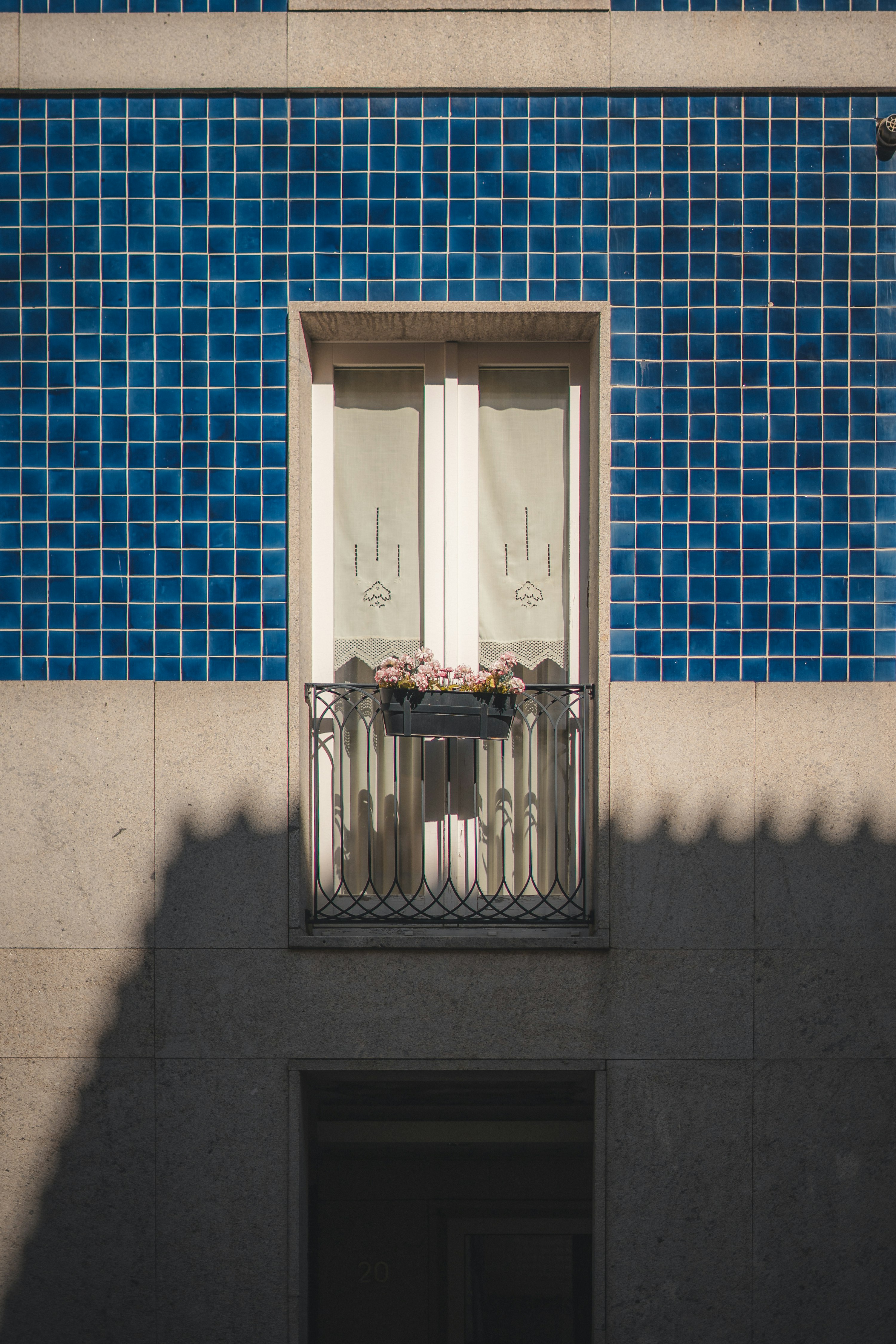 Façade d'azulejos bleus de Porto avec un balcon fleuri en fer forgé — carreaux de faïence bleus et blancs typiques de la ville.