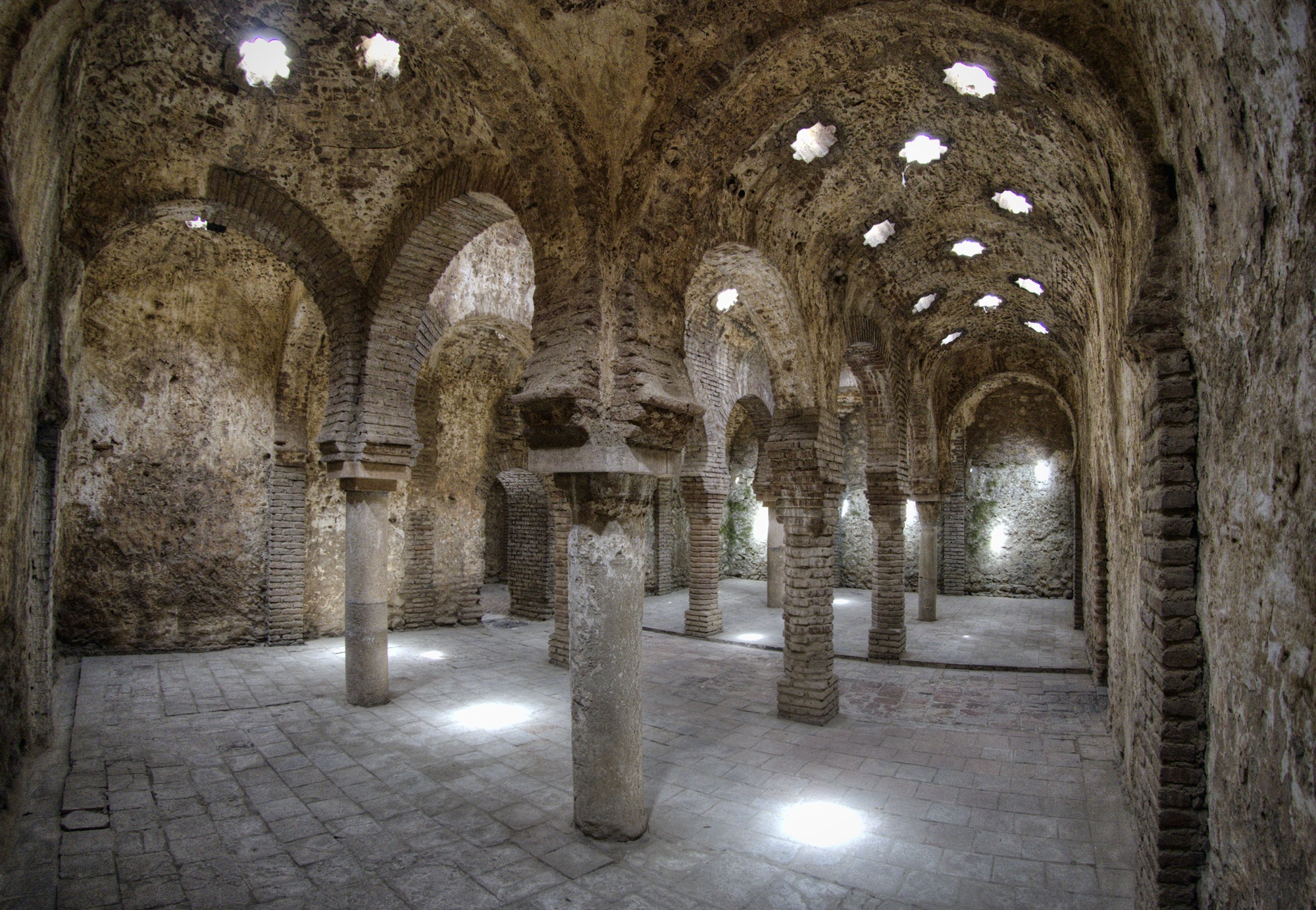 Salle voûtée des Baños Árabes de Ronda, arcs en fer à cheval et lucarnes en étoile