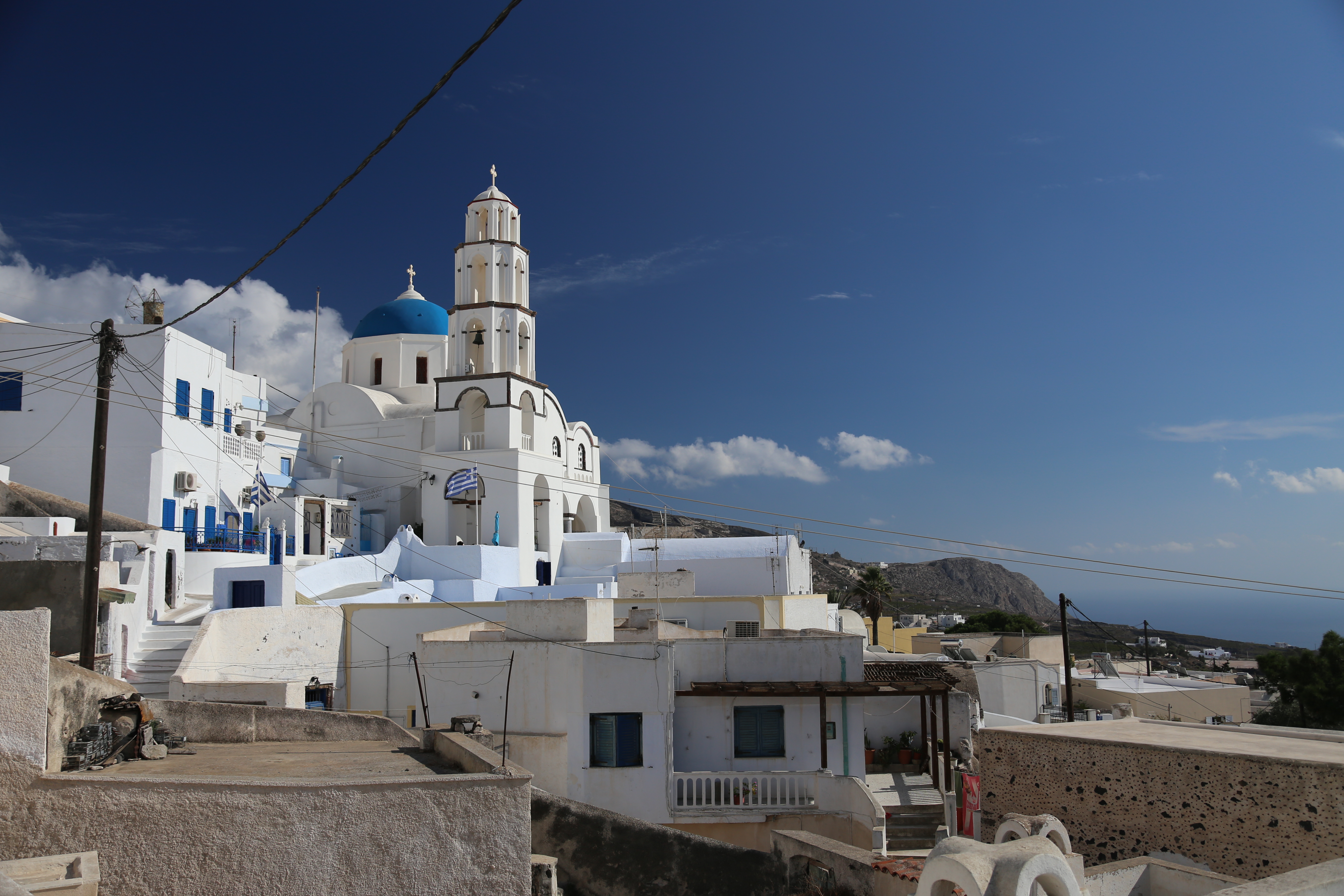 Le village de Pyrgos accroché à sa colline, église à dôme bleu et clocher blanc, à Santorin