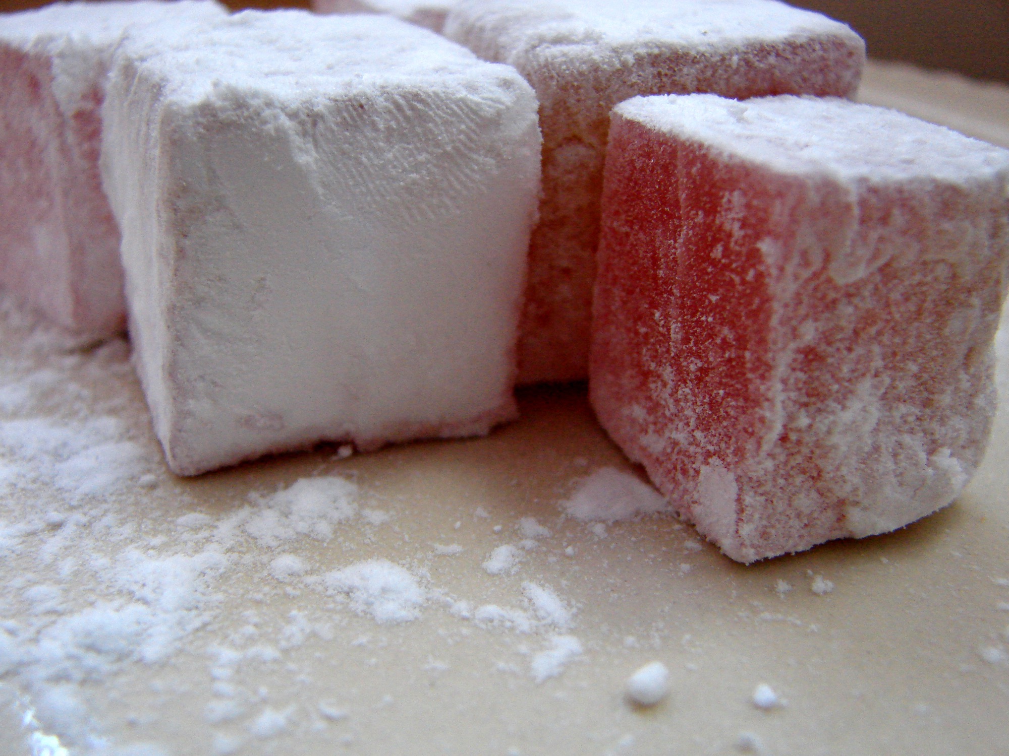 Des cubes de loukoumi (loukoum), blanc et rose, généreusement saupoudrés de sucre glace, en gros plan